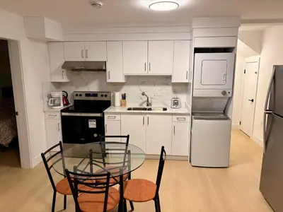 a kitchen with white cabinets and a glass table and chairs at Cozy Private Suite in Langley in Langley