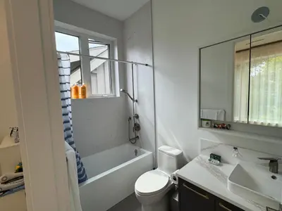 a bathroom with a sink and a toilet and a mirror at New Lux House on Vancouver West in Vancouver