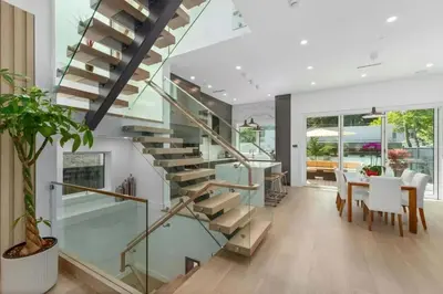 a glass staircase in a home with a table and a dining room at New Lux House on Vancouver West in Vancouver