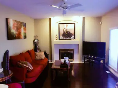 a living room with a red couch and a fireplace at Sandy's Sweet Home in Coquitlam
