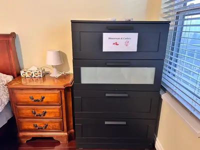 a black dresser with a sign on it next to a night stand at Sandy's Sweet Home in Coquitlam