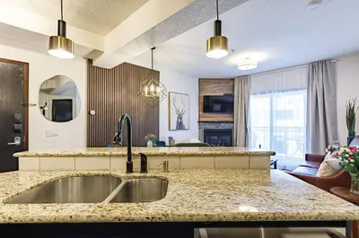 a kitchen with a sink and a living room at Westwinds - Funky Basecamp in the Rockies in Canmore