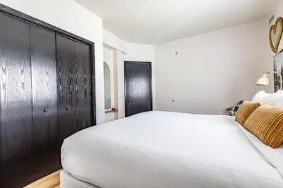 a bedroom with a white bed and a wooden closet at Westwinds - Funky Basecamp in the Rockies in Canmore