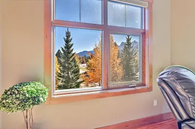 a window with a view of trees and mountains at McAuley Manor - Mountain Views Downtown Location in Canmore