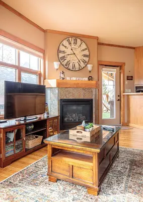 a living room with a fireplace and a clock on the wall at McAuley Manor - Mountain Views Downtown Location in Canmore