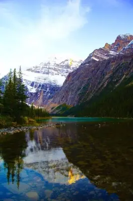 a reflection of a mountain in a body of water at McAuley Manor - Mountain Views Downtown Location in Canmore