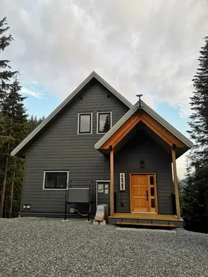 a black house with a brown door in front of it at Après-Ski Lodge in Agassiz