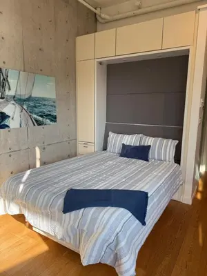 a bedroom with a large bed with a painting on the wall at Downtown Studio Rental in Victoria