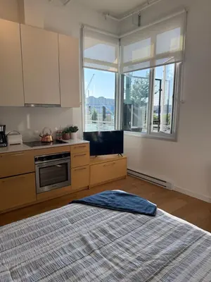 a bedroom with a bed and a kitchen with windows at Downtown Studio Rental in Victoria