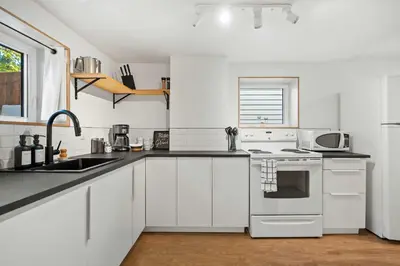 a white kitchen with a sink and a stove at The Sunny 2 Suites 10 Pax Pet Friendly Stay in Calgary