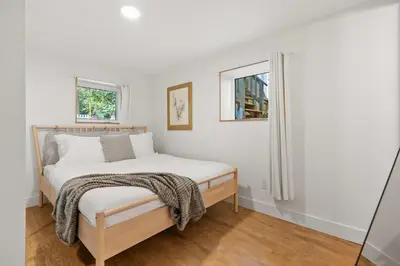 a white bedroom with a bed and two windows at The Sunny 2 Suites 10 Pax Pet Friendly Stay in Calgary
