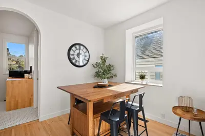 a dining room with a table and chairs and a clock at The Lokal 2 Kings Queen Suite in Sunnyside YYC in Calgary