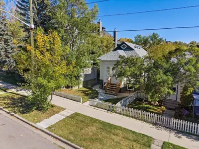 a white house with a fence in a yard at The Sunday Charming Private Suite in Calgary in Calgary