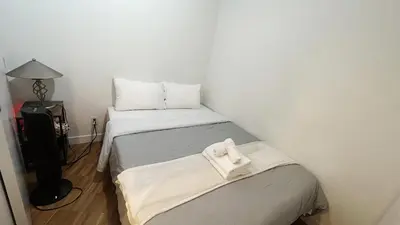 a small room with two beds and a lamp at Urban Calm, Comfort in the Heart of the City in Vancouver
