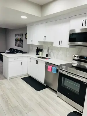 a kitchen with white cabinets and stainless steel appliances at Modern 2-bed 1-bath Suite in Calgary