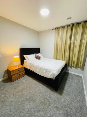 a bedroom with a bed and a table with a lamp at Modern 2-bed 1-bath Suite in Calgary