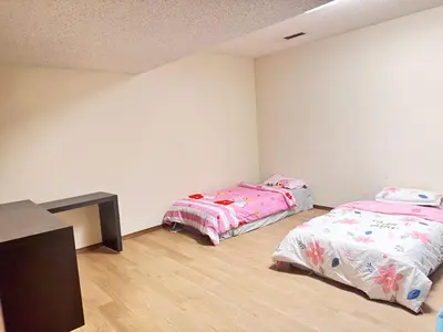 a room with two beds and a table in it at Only 7 km from YYC Sandstone Homestay in Calgary