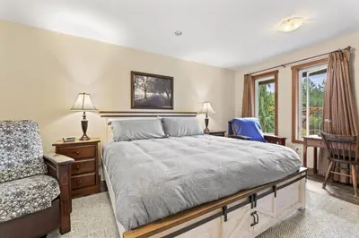 a bedroom with a bed and a chair and a window at Ackerview Guesthouse Bed and Breakfast in Salmon Arm