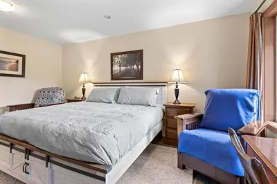 a bedroom with a bed and a blue chair at Ackerview Guesthouse Bed and Breakfast in Salmon Arm