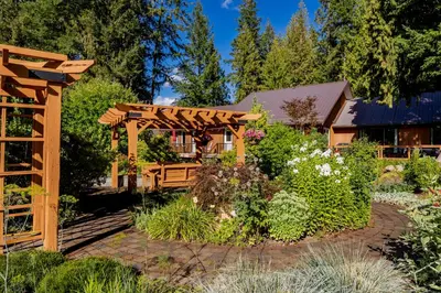 a wooden pergola in the middle of a garden at Ackerview Guesthouse Bed and Breakfast in Salmon Arm