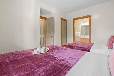 a room with two beds with purple sheets and a tray of coffee cups at Lodges at Canmore Resort in Canmore