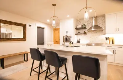 a kitchen with white cabinets and black bar stools at Luxury Spring Creek Condo with Hot Tub in Canmore