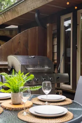 a grill sitting on a table with plates and glasses at South Swell Tofino (formerly Blue Heron Waterfront Home amid Old Growth Cedars) in Tofino
