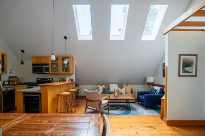 a room with a kitchen and a living room at South Swell Tofino (formerly Blue Heron Waterfront Home amid Old Growth Cedars) in Tofino