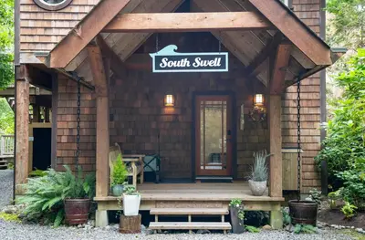 a small cabin with a sign that reads south sweet at South Swell Tofino (formerly Blue Heron Waterfront Home amid Old Growth Cedars) in Tofino