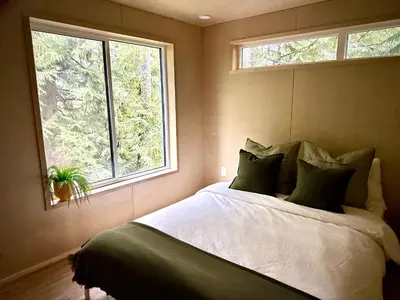 a bedroom with a large bed and a window at Riverside Retreat in Cowichan Bay