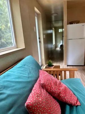 two red pillows sitting on a blue couch with a window at Riverside Retreat in Cowichan Bay