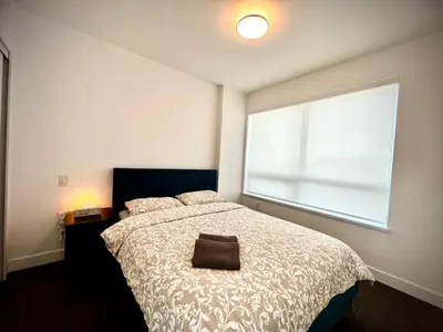 a bedroom with a bed and a large window at Mordern stylish 2B2B close to Richmond center in Richmond