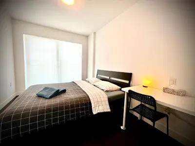 a bedroom with a bed and a desk and a window at Mordern stylish 2B2B close to Richmond center in Richmond