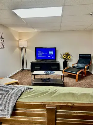 a room with a tv and a bed and a chair at Beautiful Suite Fenced yard Kitchen Laundry in St. Albert