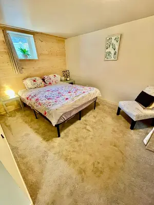 a bedroom with a bed and a window and a chair at Beautiful Suite Fenced yard Kitchen Laundry in St. Albert