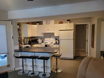 a kitchen with white cabinets and bar stools at Beautiful Mountain Retreat with a View in Abbotsford