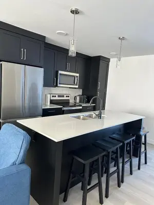 a kitchen with black cabinets and a kitchen island with stools at Modern new townhouse in Red Deer