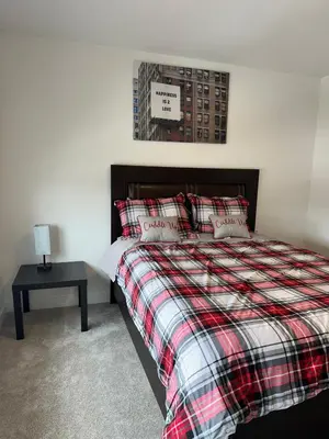 a bedroom with a bed with a plaid blanket and a table at Modern new townhouse in Red Deer
