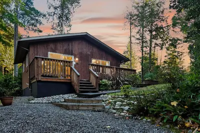 a cabin in the woods with a deck and stairs at Little Bear Cabin at Raven's Moon in Ucluelet