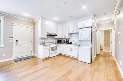 a white kitchen with white appliances and wooden floors at Cozy two beds lower level suite in Vancouver West in Vancouver