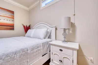 a white bedroom with a bed and a lamp at Cozy two beds lower level suite in Vancouver West in Vancouver