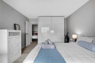 a bedroom with a large bed with a blue rug at Central Downtown at Rocky Mountain Court with Gym, Court, Sauna and Secured Parking in Calgary