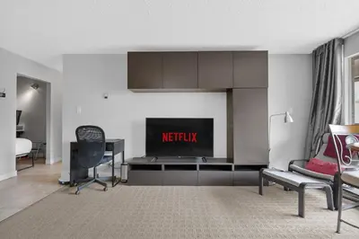 a living room with a tv and a desk with a chair at Central Downtown at Rocky Mountain Court with Gym, Court, Sauna and Secured Parking in Calgary