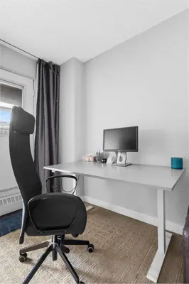 a desk with a computer monitor and a chair at Central Downtown at Rocky Mountain Court with Gym, Court, Sauna and Secured Parking in Calgary