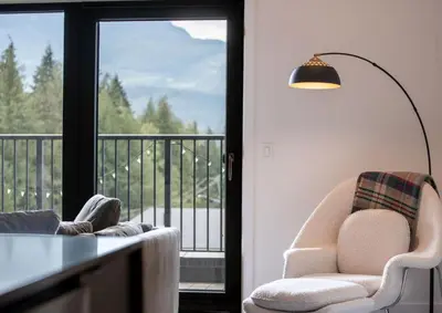 a living room with a chair and a table and a balcony at The Begbie Penthouse in Mackenzie Village in Revelstoke