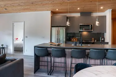 a kitchen with a bar with blue chairs in a room at The Begbie Penthouse in Mackenzie Village in Revelstoke