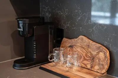 a coffee maker with glasses on a wooden cutting board at The Begbie Penthouse in Mackenzie Village in Revelstoke