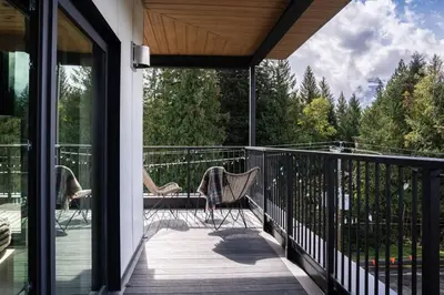 a balcony with two chairs and a view of trees at The Begbie Penthouse in Mackenzie Village in Revelstoke