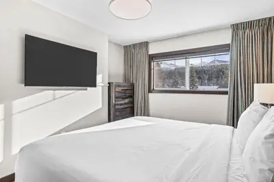 a bedroom with a bed and a flat screen tv at Bears Den 2BR Getaway with Hot Tub, BBQ Near DT in Dead Man's Flats