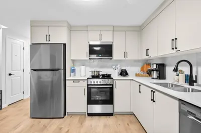 a kitchen with white cabinets and a stainless steel refrigerator at Brand New Cozy2BR House NW Calgary DT Banff Sleep4 in Calgary